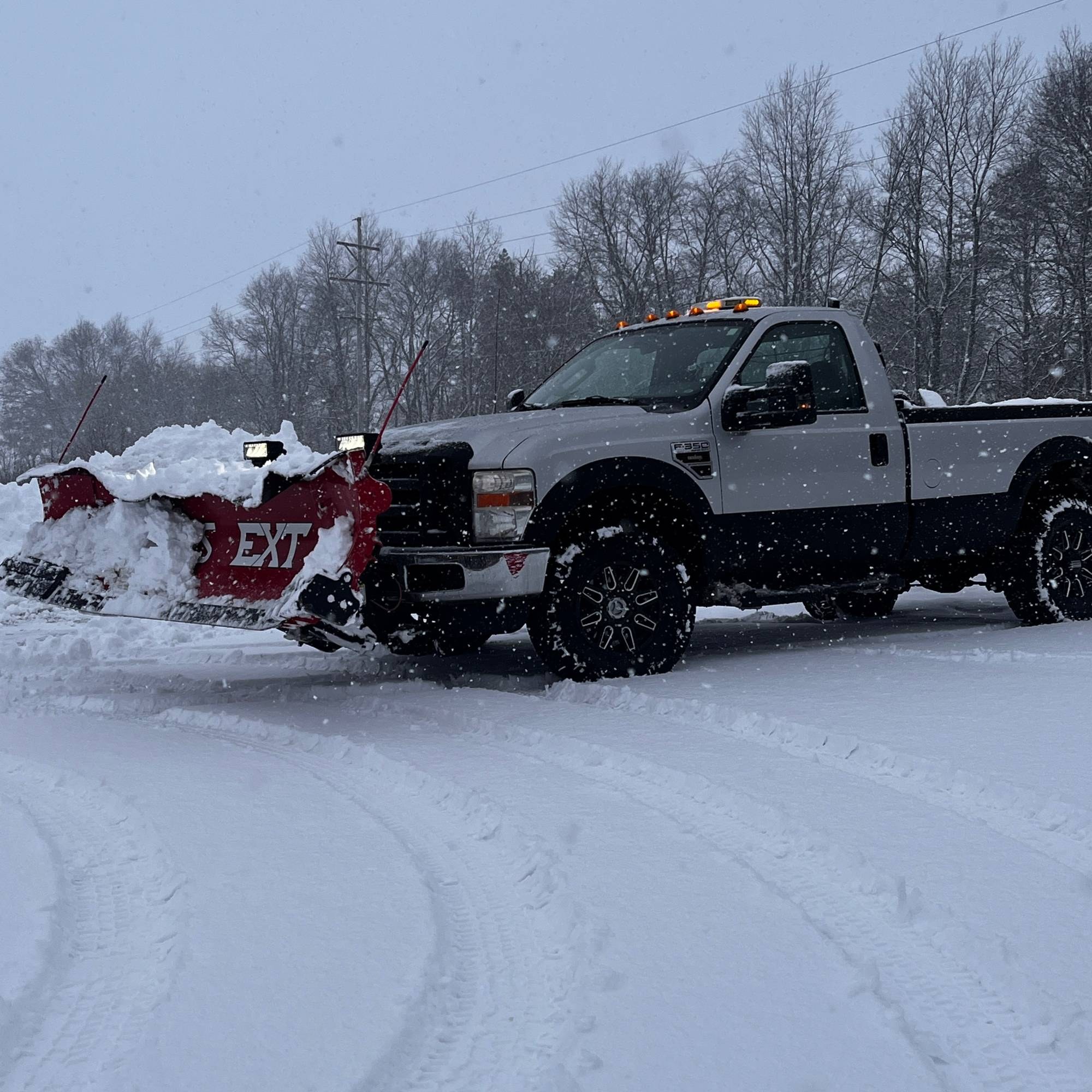 Freedom Lawn Care & Snow Removal plow truck pushing snow with a red V-plow on a snowy lot